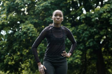 Parkta gerinen siyah bayan sporcunun portresi. Siyah etek giyiyor..