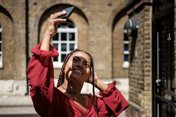 Akıllı telefonlu genç bir kadın sıcak bir yaz gününde Londra sokaklarında selfie çekiyor..