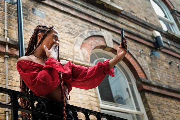 Akıllı telefonlu genç bir kadın sıcak bir yaz gününde Londra sokaklarında selfie çekiyor..