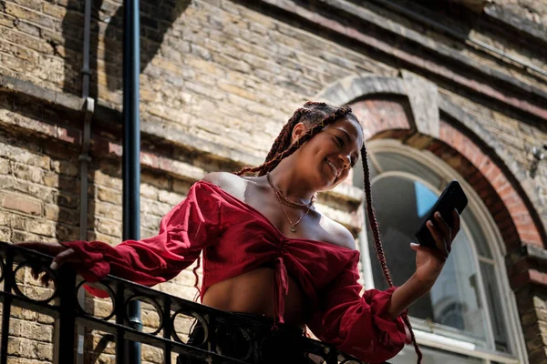 Akıllı telefonlu genç bir kadın sıcak bir yaz gününde Londra sokaklarında selfie çekiyor..