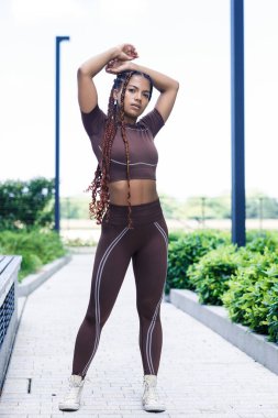 Spor giyinen ve esneme hareketleri yapan genç bir kadın. Karışık ırk, örgü..