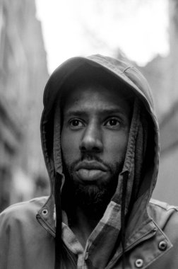 Kapüşonlu ceketli ciddi bir gencin klasik sokak fotoğrafçılığını anımsatan klasik ve atmosferik bir titreşim uyandıran tek renkli, analog film portresi.