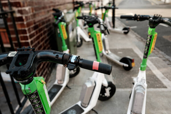 Lime electric scooters parked in a row on a city trowalk, showcasing sustainable shared mobility, convenient short-distance travel and eco-friendly urban transport solutions
