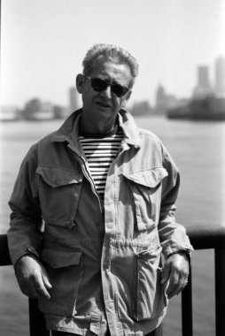 Grainy monochrome analog vinog fotoğraf ihtiyarlar güneş gözlüğü ve ceket giyerek nehirde poz verirler, arka planda bulanık şehir manzarası vardır.