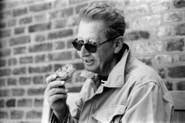 Yaşlı bir adamın güneş gözlüğü takıp elinde lezzetli bir hamur işi tutarken klasik 35 mm 'lik film estetiğiyle nostaljik bir atmosferi anımsattığı tek renkli, klasik bir fotoğraf.