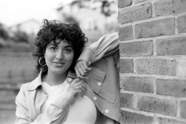 Duvara yaslanmış, klasik bir 35 mm film estetiği ile yakalanmış, zamansız ve nostaljik bir duygu yayan genç bir kadının taneli tek renkli analog portresi.