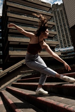 Barbican malikânesinde, Londra 'da beton bir merdivende dans eden zarif bir dansçı, çağdaş dans ve şehir estetiğinin bir füzyonunu vahşi mimarinin arka planına karşı sergiliyor.