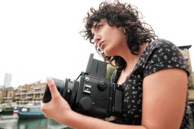 Genç fotoğrafçı orta formatlı bir kamerayla Londra 'daki St. Katharine rıhtımının cazibesini yakalıyor. Konut binaları ve demirlemiş tekneleri de manzaraya ekliyor.