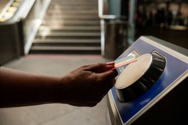 Otomatik bir makinenin kredi kartı ile ulaşılamaz bir kredi kartı kullanan, metro, otobüs ya da tren bileti alan, arka plandaki bulanık merdivenlerden görülebilen yolcular