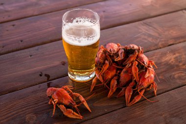 Full glass of beer with boiled crawfish on the table clipart