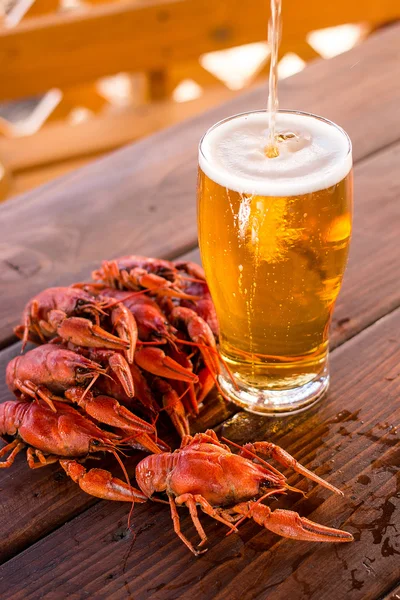 Vaso lleno de cerveza con cangrejos cocidos sobre la mesa — Foto de Stock