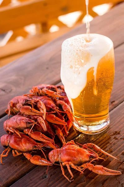 Vaso lleno de cerveza con cangrejos cocidos sobre la mesa — Foto de Stock