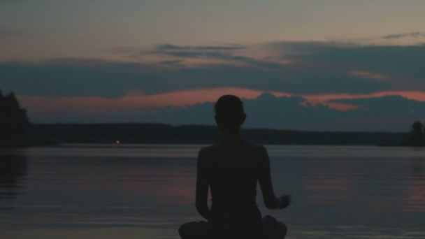 Kız bir dağın tepesinde gün batımında yoga yapar — Stok video