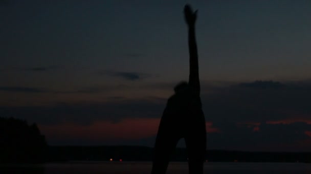 Дівчина робить йогу на заході сонця на вершині гори — стокове відео