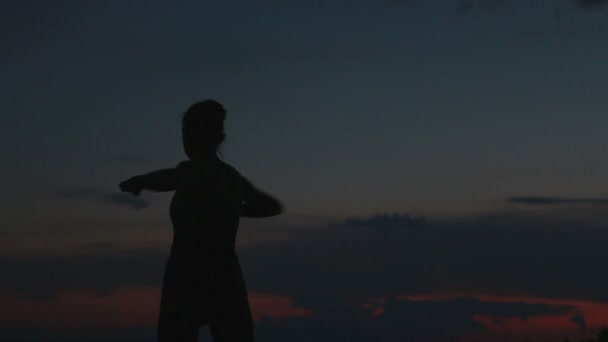 Meisje doet yoga bij zonsondergang op de top van een berg — Stockvideo