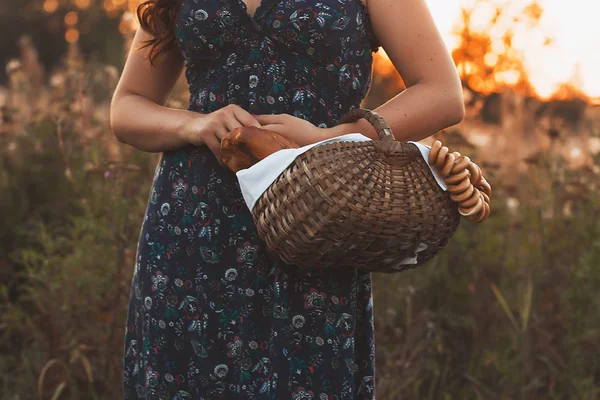 Beautiful young woman with a basket full of fresh baked bread — Stock Photo, Image