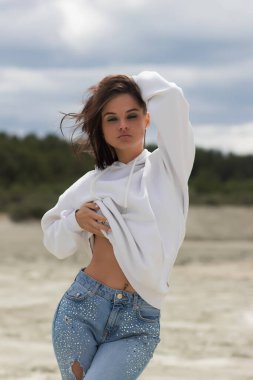 Kameraya bakan ve kırsalın bulanık arka planında kot ceketli çekici bir kadın model.