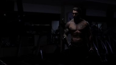 Güçlü erkek vücut geliştirici halterlerle egzersiz yapıyor.