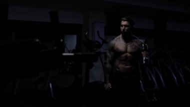 Güçlü erkek vücut geliştirici halterlerle egzersiz yapıyor.