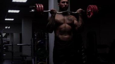 Güçlü erkek vücut geliştirici halterlerle egzersiz yapıyor.