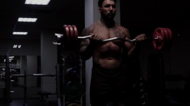 Güçlü erkek vücut geliştirici halterlerle egzersiz yapıyor.