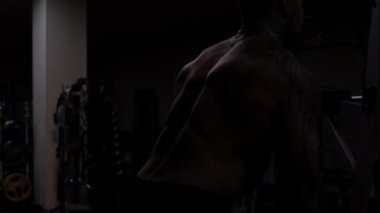 Güçlü erkek vücut geliştirici halterlerle egzersiz yapıyor.