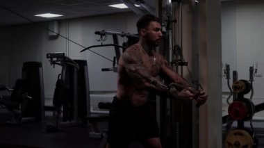 Güçlü erkek vücut geliştirici halterlerle egzersiz yapıyor.