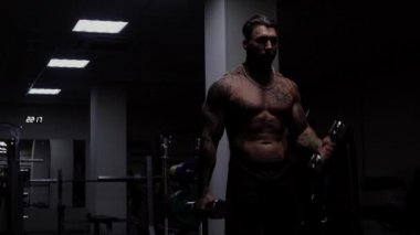 Güçlü erkek vücut geliştirici halterlerle egzersiz yapıyor.