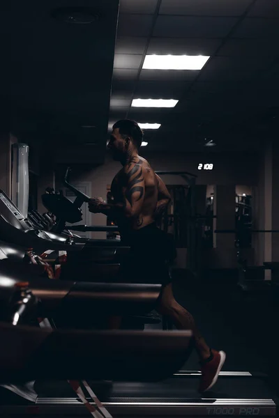 알몸의 근육질 선수가 어두운 체육관에서 운동중에 덤벨을 울리는 — 스톡 사진