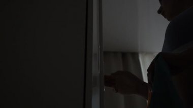 Kız dolaptan giysileri çıkarıyor.