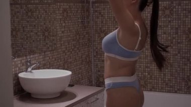 İç çamaşırlı, banyoda poz veren tanınmayan bir kadın.