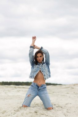 Kameraya bakan ve kırsalın bulanık arka planında kot ceketli çekici bir kadın model.