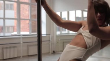 Stüdyoda direğin üstünde dans eden esnek bir kadın.