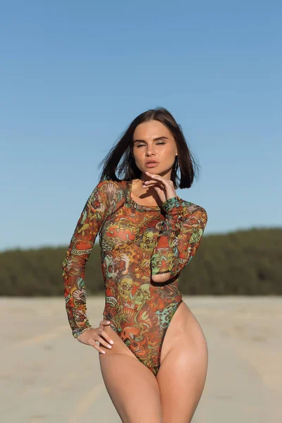 Mulher Jovem Magro Bodysuit Ornamental Tocando Cabelo Enquanto Descansa Praia — Fotografia de Stock