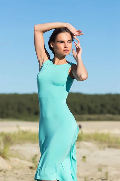 全身スリム官能的な女性で飛行髪身に着けています長いターコイズドレスながら風に立って海岸 — ストック写真