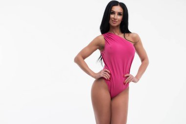 Uzun saçlı, çekici göğüslü, iç çamaşırlı esmer kadın stüdyoda kameraya bakıyor.