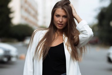 Milenyum başarılı, şık elbiseli kadın esmer yaz günü konağın bahçesinde yeşil ağaçlara karşı tek başına dikilirken kameraya bakıyor.