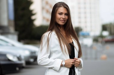 Milenyum başarılı, şık elbiseli kadın esmer yaz günü konağın bahçesinde yeşil ağaçlara karşı tek başına dikilirken kameraya bakıyor.