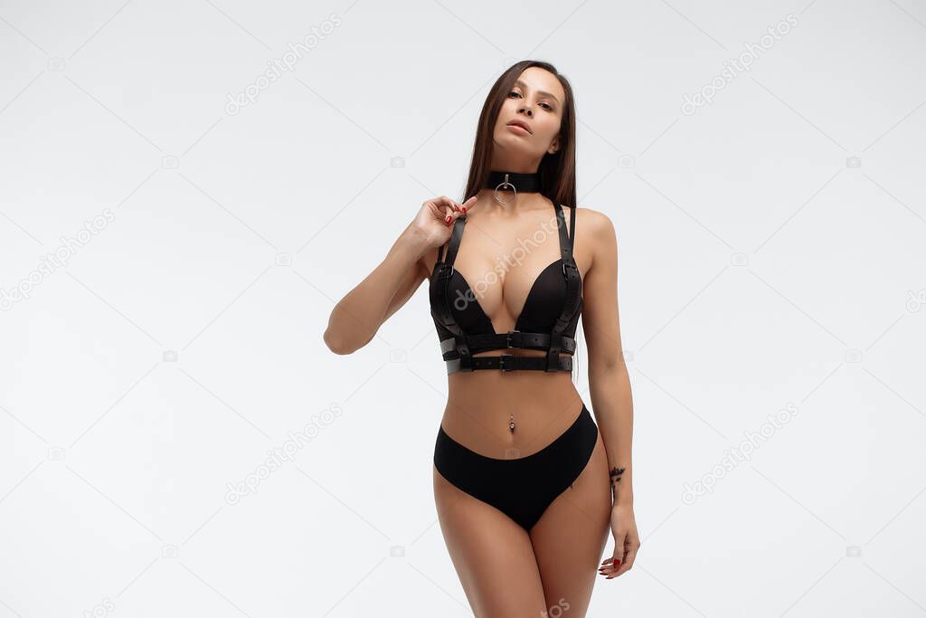 Side view of attractive erotic Hispanic young woman in lingerie crossing hands looking at camera