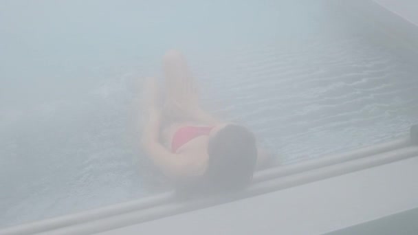 Спокуслива жінка відпочиває в басейні — стокове відео