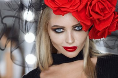 Parlak makyajlı çekici bayan gotik kıyafetler giyiyor ve stüdyoda dikilirken kameraya bakıyor.