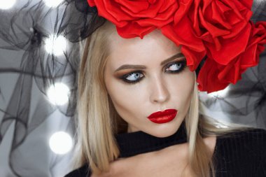 Parlak makyajlı çekici bayan gotik kıyafetler giyiyor ve stüdyoda dikilirken kameraya bakıyor.