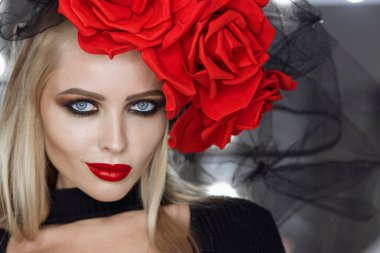 Parlak makyajlı çekici bayan gotik kıyafetler giyiyor ve stüdyoda dikilirken kameraya bakıyor.