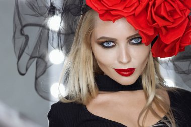 Parlak makyajlı çekici bayan gotik kıyafetler giyiyor ve stüdyoda dikilirken kameraya bakıyor.