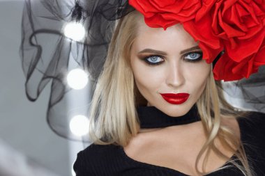 Parlak makyajlı çekici bayan gotik kıyafetler giyiyor ve stüdyoda dikilirken kameraya bakıyor.