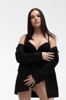 Siyah iç çamaşırlı, zayıf, baştan çıkarıcı bir kadın kameraya bakarken kendini kucaklıyor.