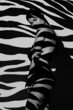 Vücudunda gölgesi olan zarif çıplak bir kadının moda sanat stüdyosu portresi.