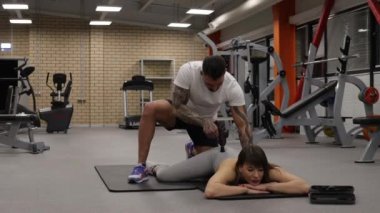 Spor kadının vücuduna masaj tabancası kullanan kişisel antrenör.
