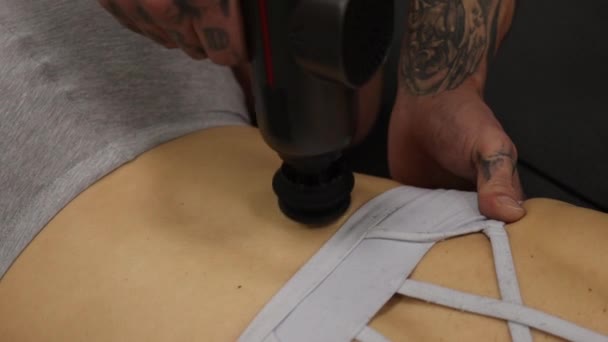 Personal trainer met behulp van massage pistool op het lichaam van sportvrouw — Stockvideo