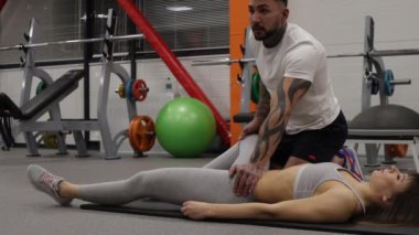 Spor salonundaki spor kadının bacaklarını açan kişisel antrenör.